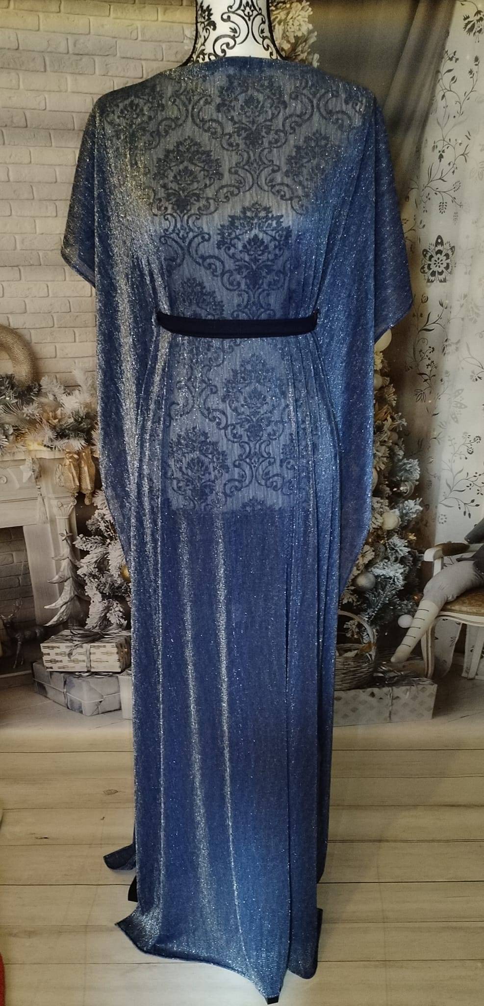 Un robe façon cape au tissu bleu pailleté argenté, se noue avec une ceinture dans le dos 